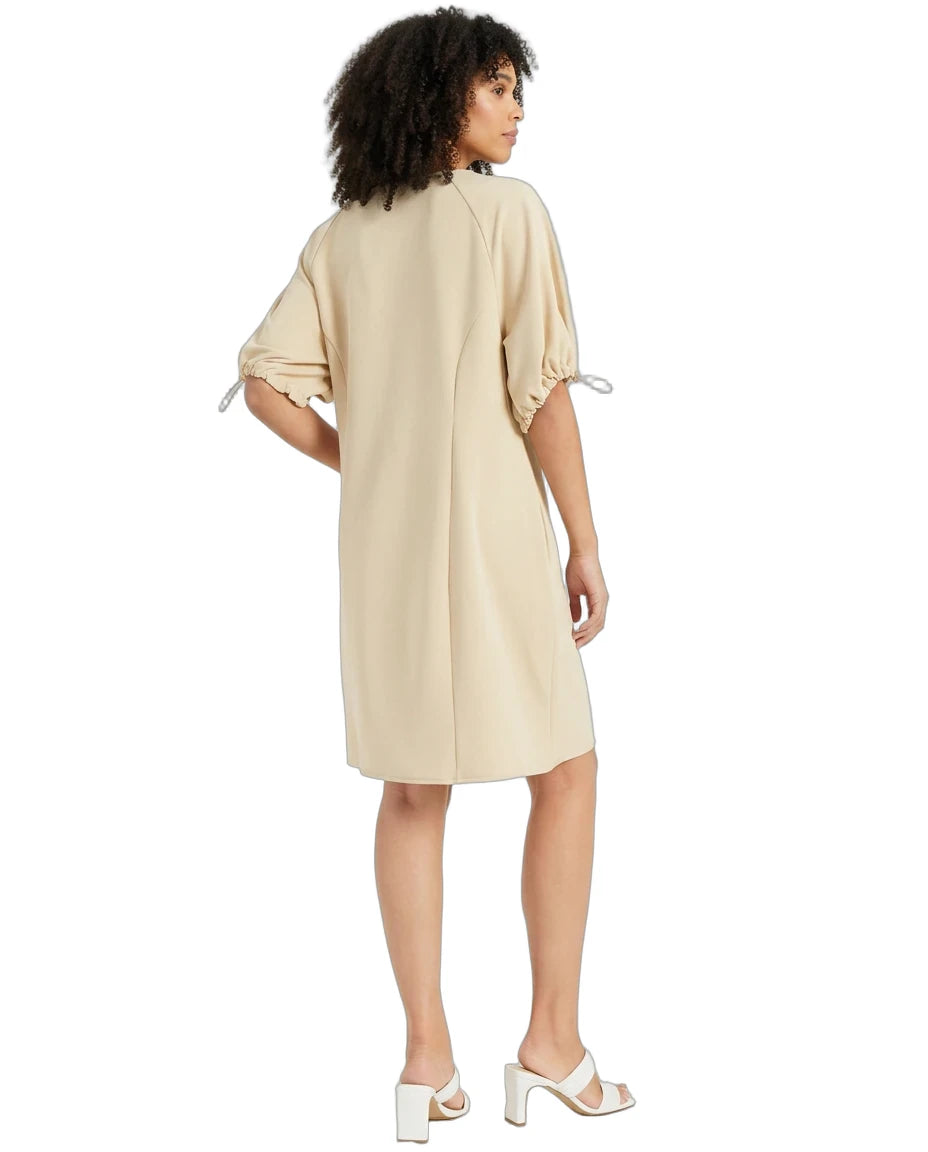 A woman modeling a light beige midi dress from the back, featuring short puff sleeves with tie details, on a solid white background.