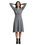 A woman modeling a gray long-sleeve wrap-style dress with a V-neckline and flared skirt, paired with black ankle boots, against a plain white background.