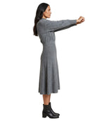 A woman modeling a gray long-sleeve knit midi dress with a gathered waist, shown in profile against a plain white background.