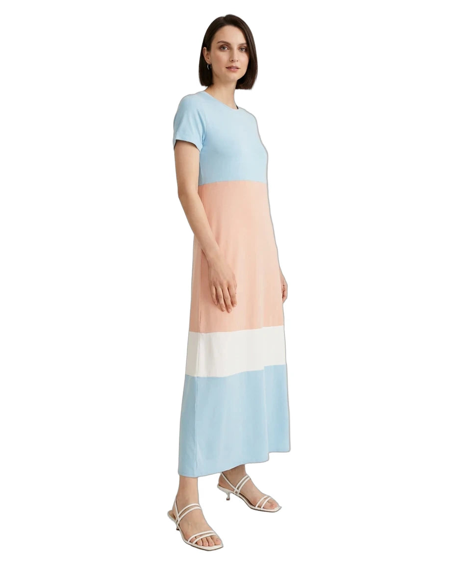 A woman modeling a color-block midi dress with short sleeves, featuring horizontal stripes of light blue, peach, white, and light blue, paired with white strappy sandals on a white background.