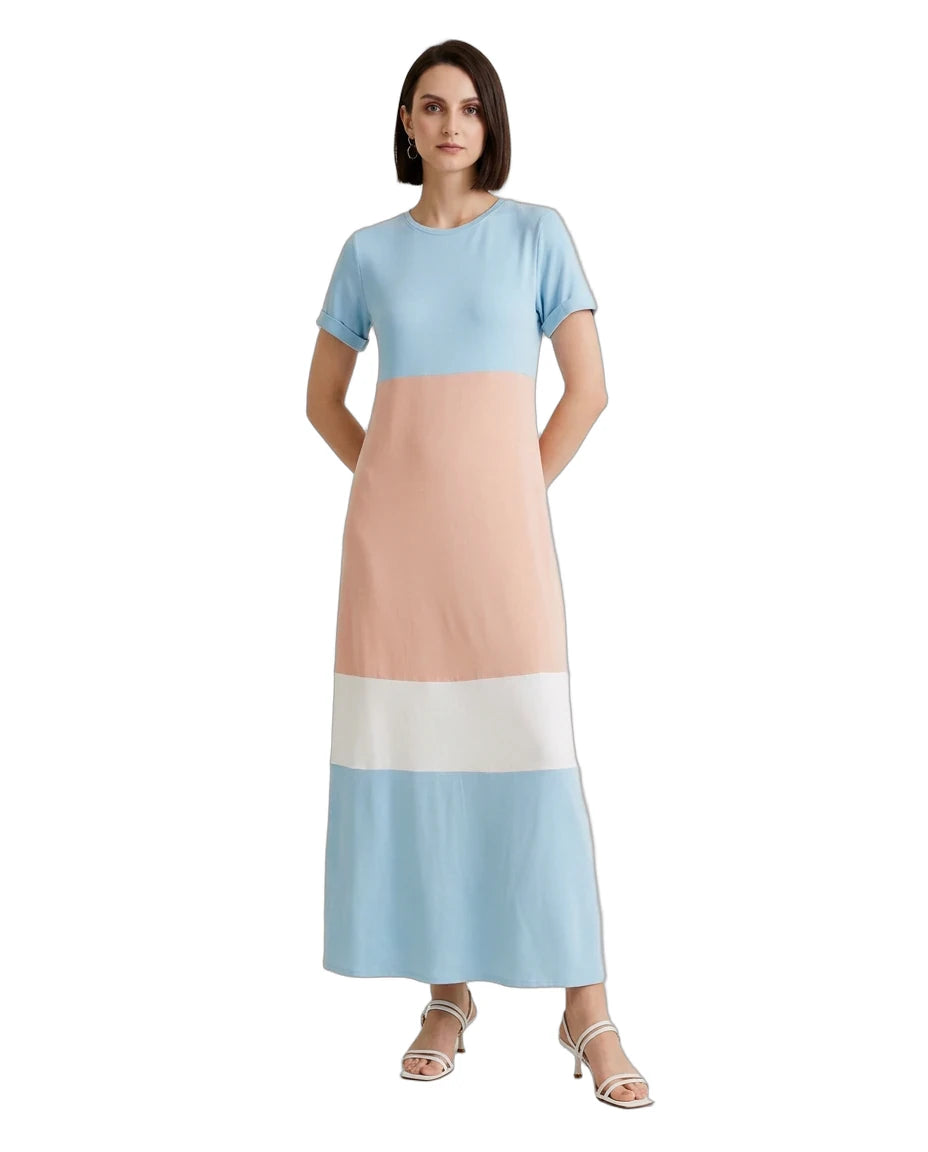 A woman modeling a short-sleeve maxi dress with a colorblock design in light blue, peach, white, and light blue, paired with white heeled sandals against a plain white background.