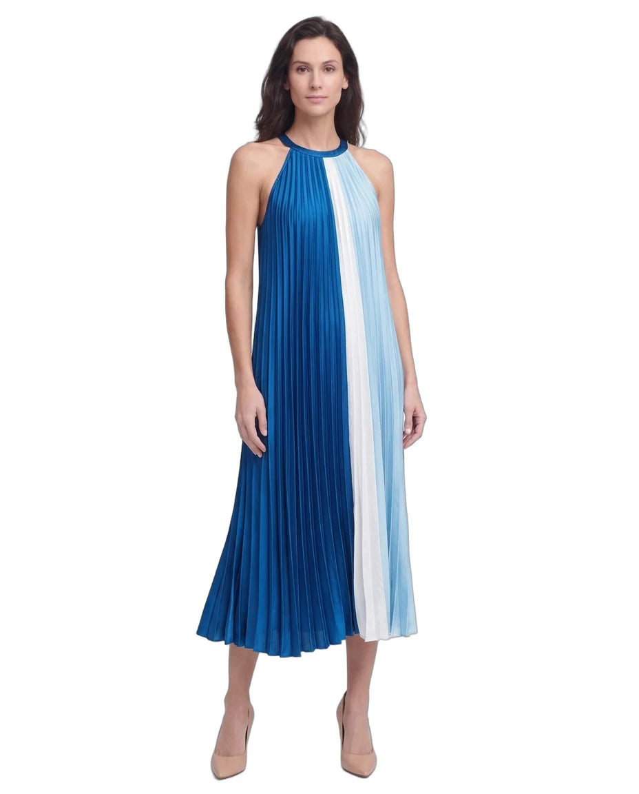 A woman modeling a sleeveless halter-neck midi dress with vertical pleated stripes in royal blue, white, and light blue, paired with nude heels, against a plain white background.