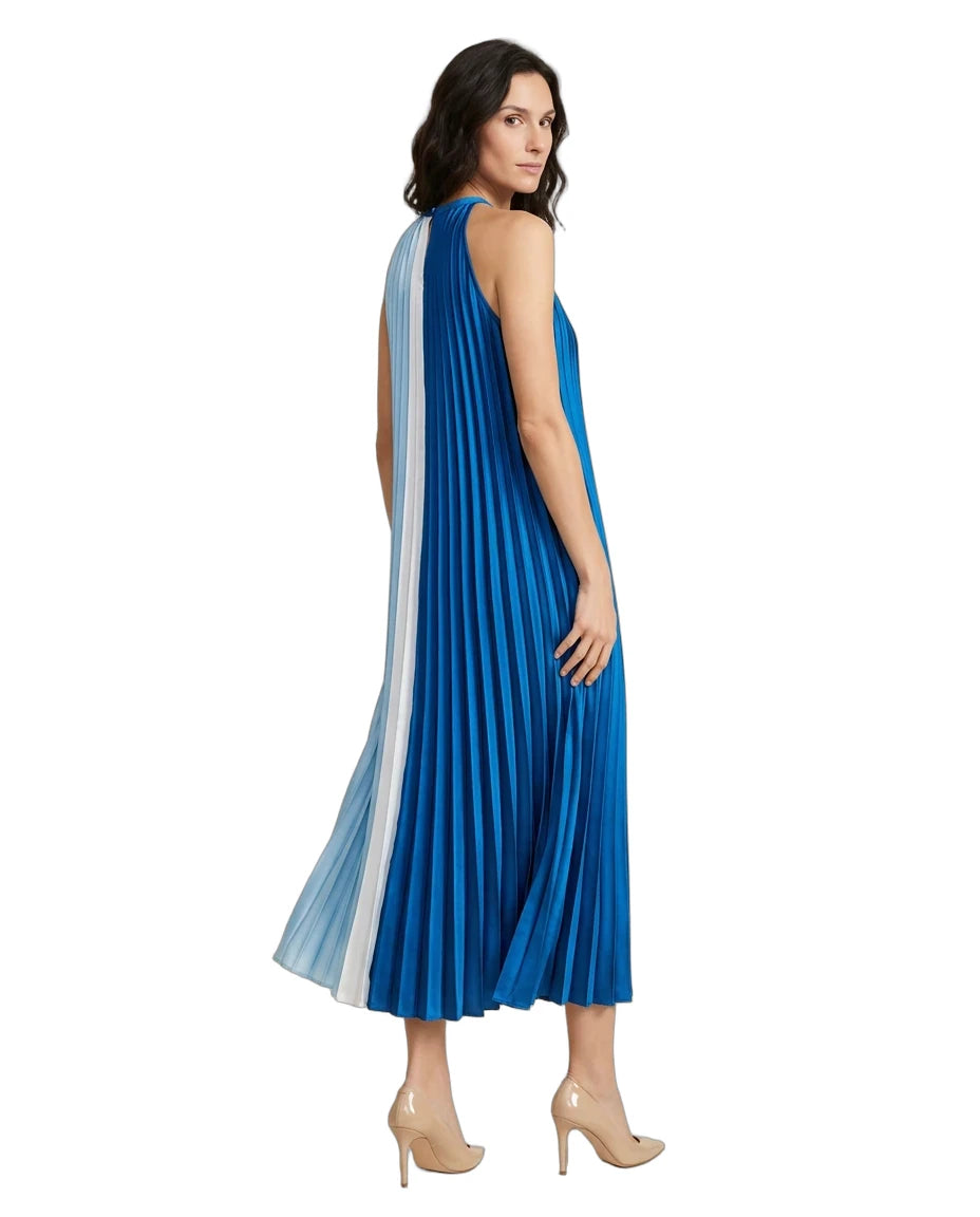 A woman modeling a sleeveless pleated midi dress with a vertical striped panel in shades of blue, white, and light blue, paired with beige high heels against a plain white background.