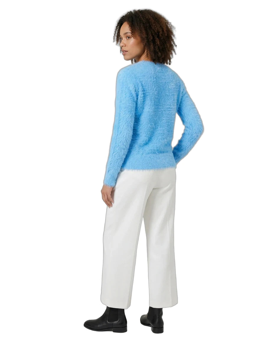 A woman shown from the back wearing a fuzzy light blue long-sleeve sweater, white wide-leg trousers, and black ankle boots against a plain white background.