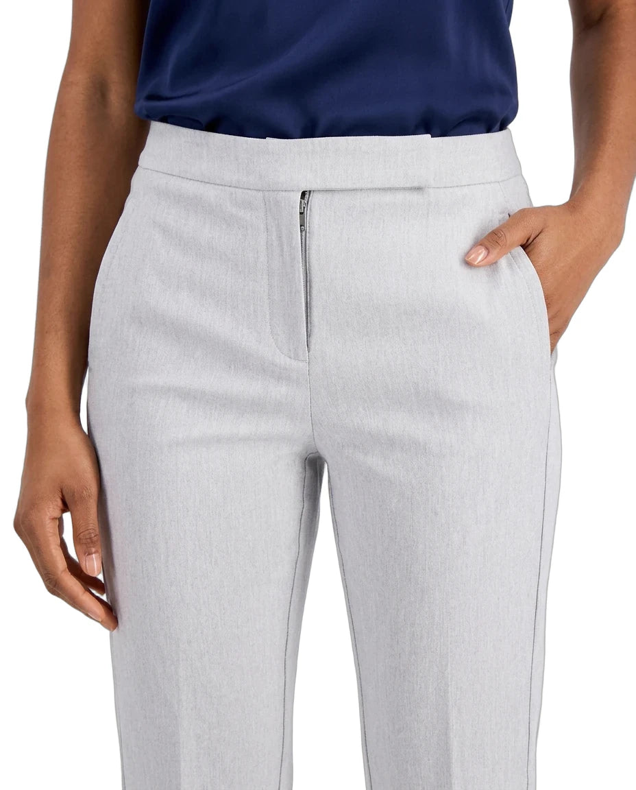 A close-up of a model wearing light gray tailored trousers with a front zipper, paired with a navy top against a plain white background.