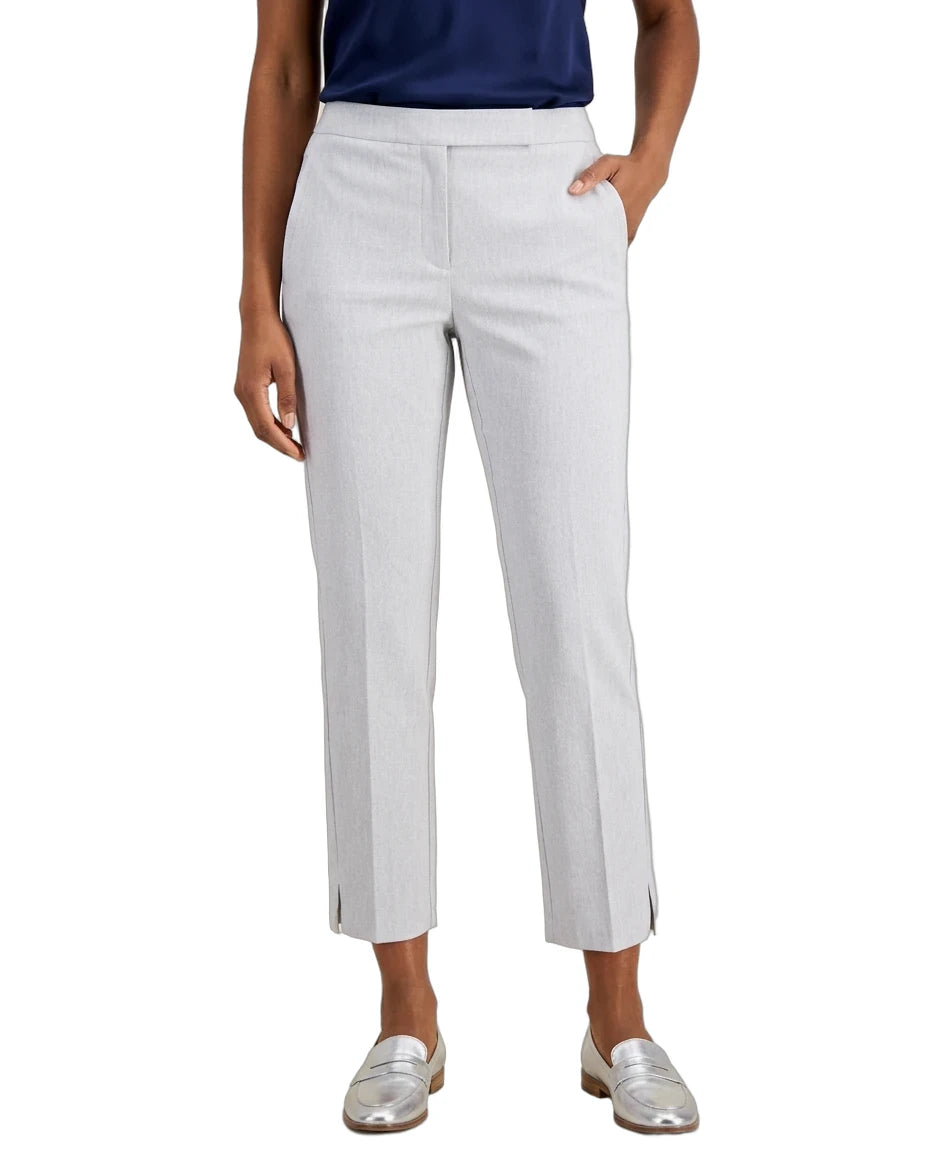 A model wearing light gray cropped trousers with side slits, paired with a navy top and metallic silver loafers, shown against a plain white background.