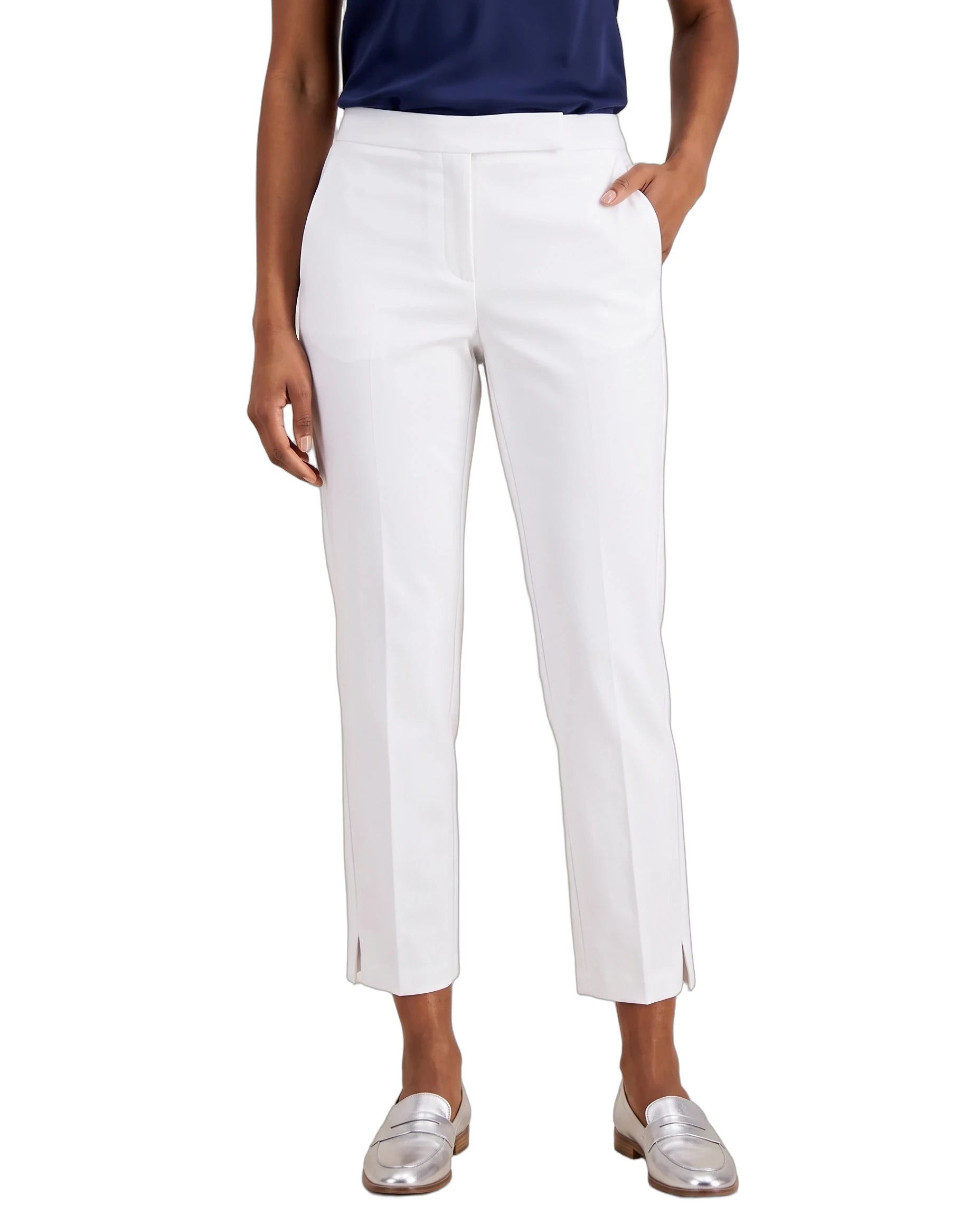 A model wearing white cropped trousers with side slits, paired with a navy top and metallic silver loafers, shown against a plain white background.