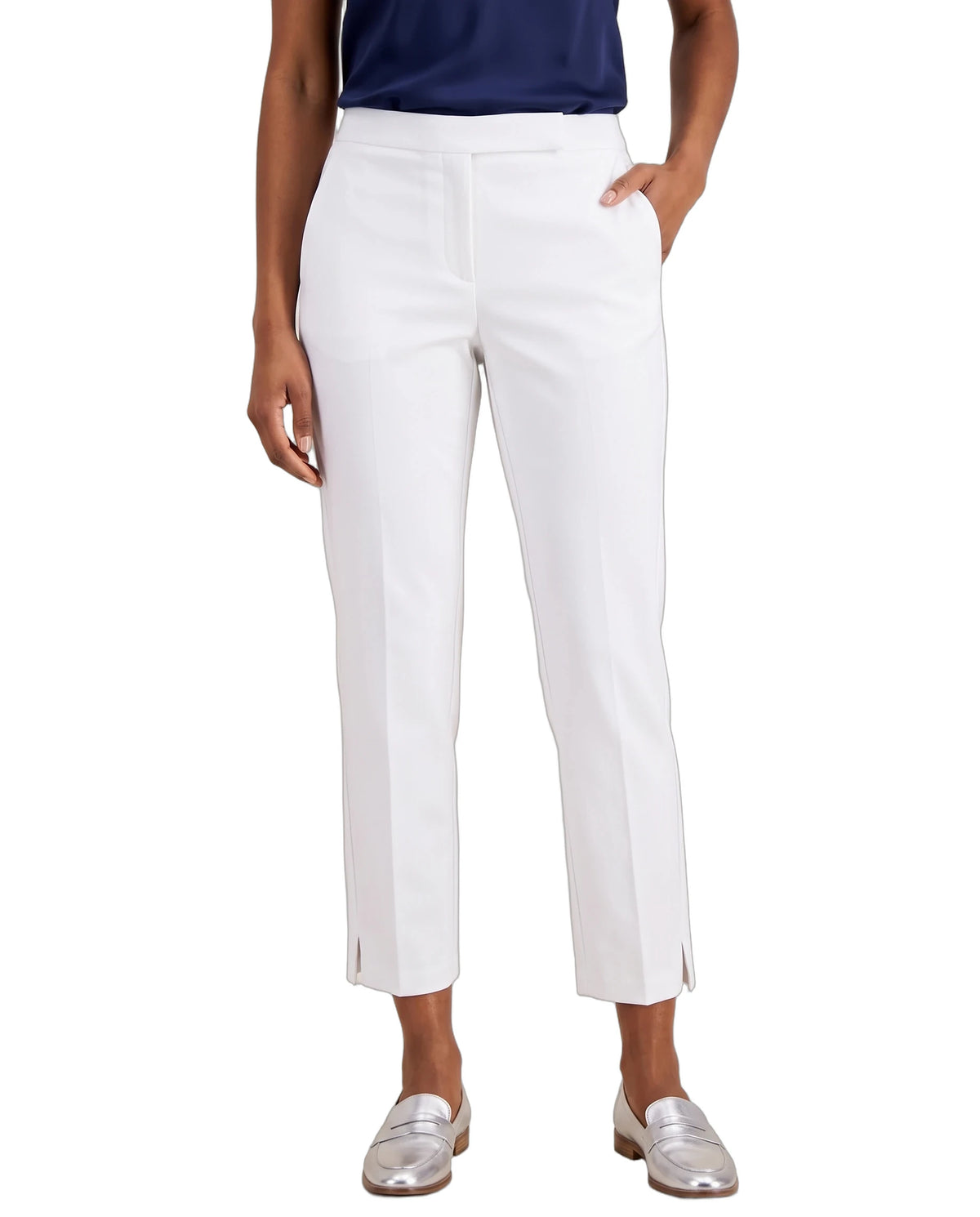 A model wearing white cropped trousers with side slits, paired with a navy top and metallic silver loafers, shown against a plain white background.