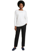 Person wearing a white sweater and black pants on a white background