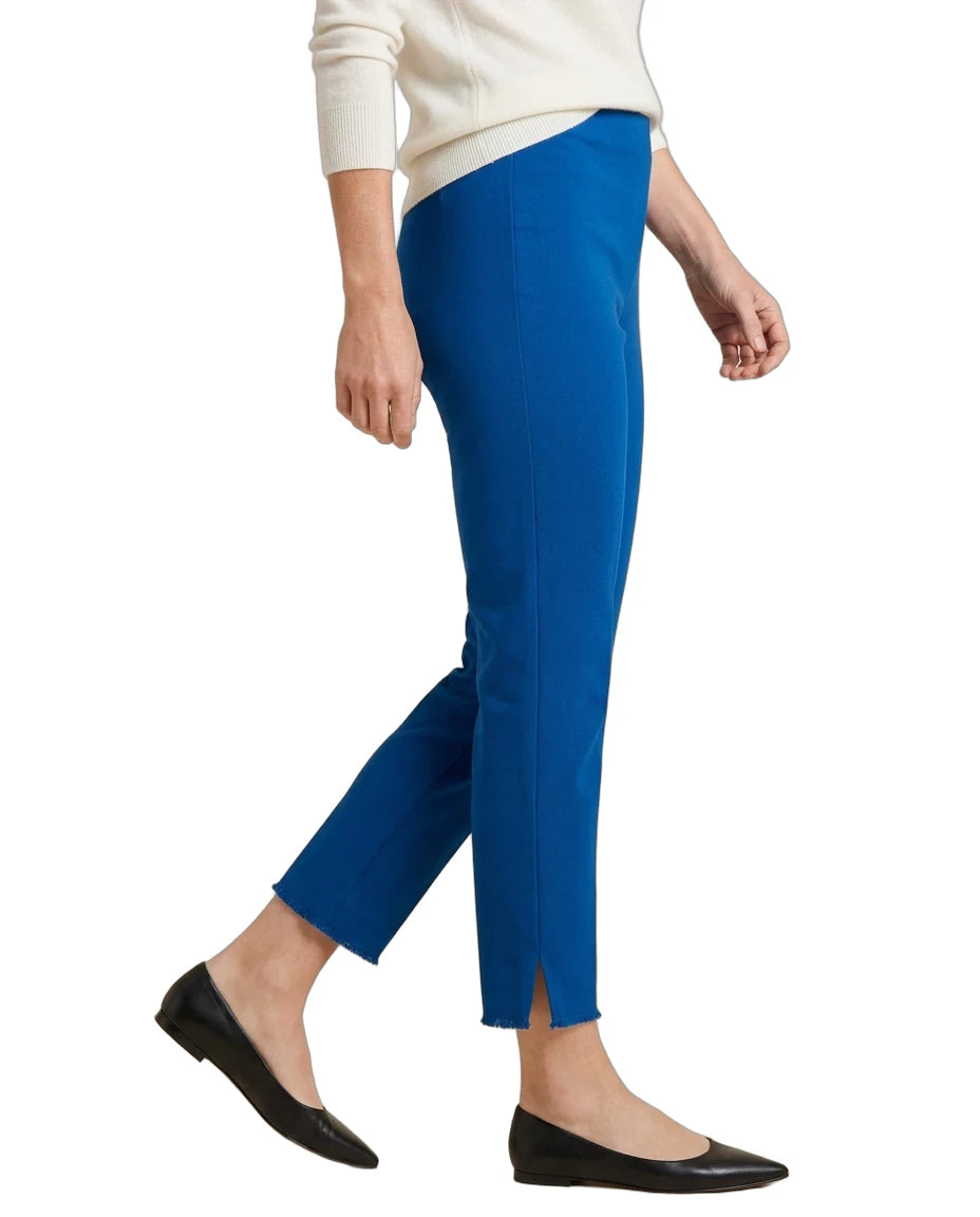 A person wearing bright royal blue cropped pants with side slits, styled with a cream sweater and black flats against a plain white background.