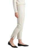 A side-profile view of a person wearing off-white cropped trousers with side slits at the ankles, paired with black flats and a cream sweater, against a plain white background.