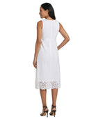 A woman shown from the back wearing a sleeveless white midi dress with a textured woven pattern and eyelet lace trim at the hem, paired with black high-heeled sandals against a plain white background.