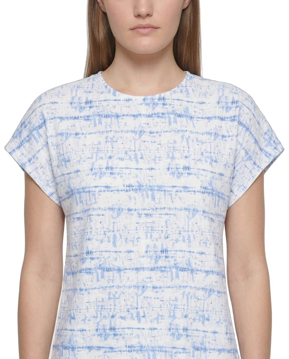 A woman wearing a short-sleeve crewneck top with a blue and white abstract horizontal stripe pattern, shown against a plain white background.