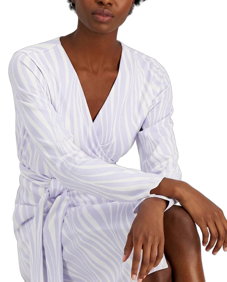 A woman wearing a white wrap-style long-sleeve dress with a light lavender-purple zebra-like stripe pattern, shown from the chest down against a plain white background.