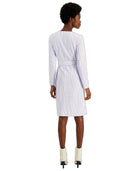 A woman shown from the back wearing a white long-sleeve belted dress with a subtle vertical wavy stripe pattern, paired with white ankle boots, against a plain white background.