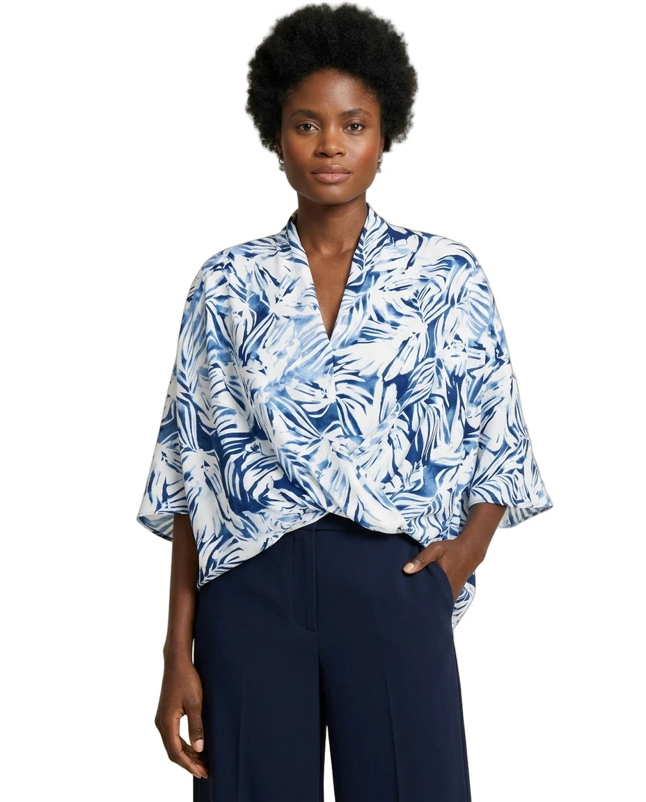 Woman wearing a blue and white patterned blouse with navy pants on a white background