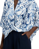 Blue and white patterned top worn by a person with a dark background