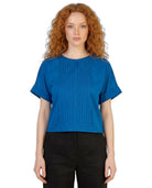 Woman wearing a blue top and black pants on a white background