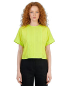Woman wearing a bright green blouse and black pants on a white background