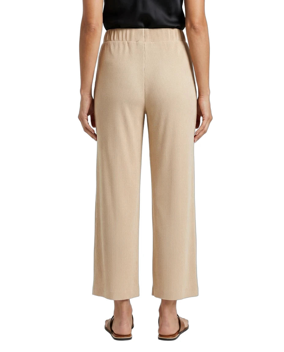A person shown from the back wearing high-waisted, wide-leg cropped pants in a light beige or sand color, paired with a black top and flat sandals, against a plain white studio background.