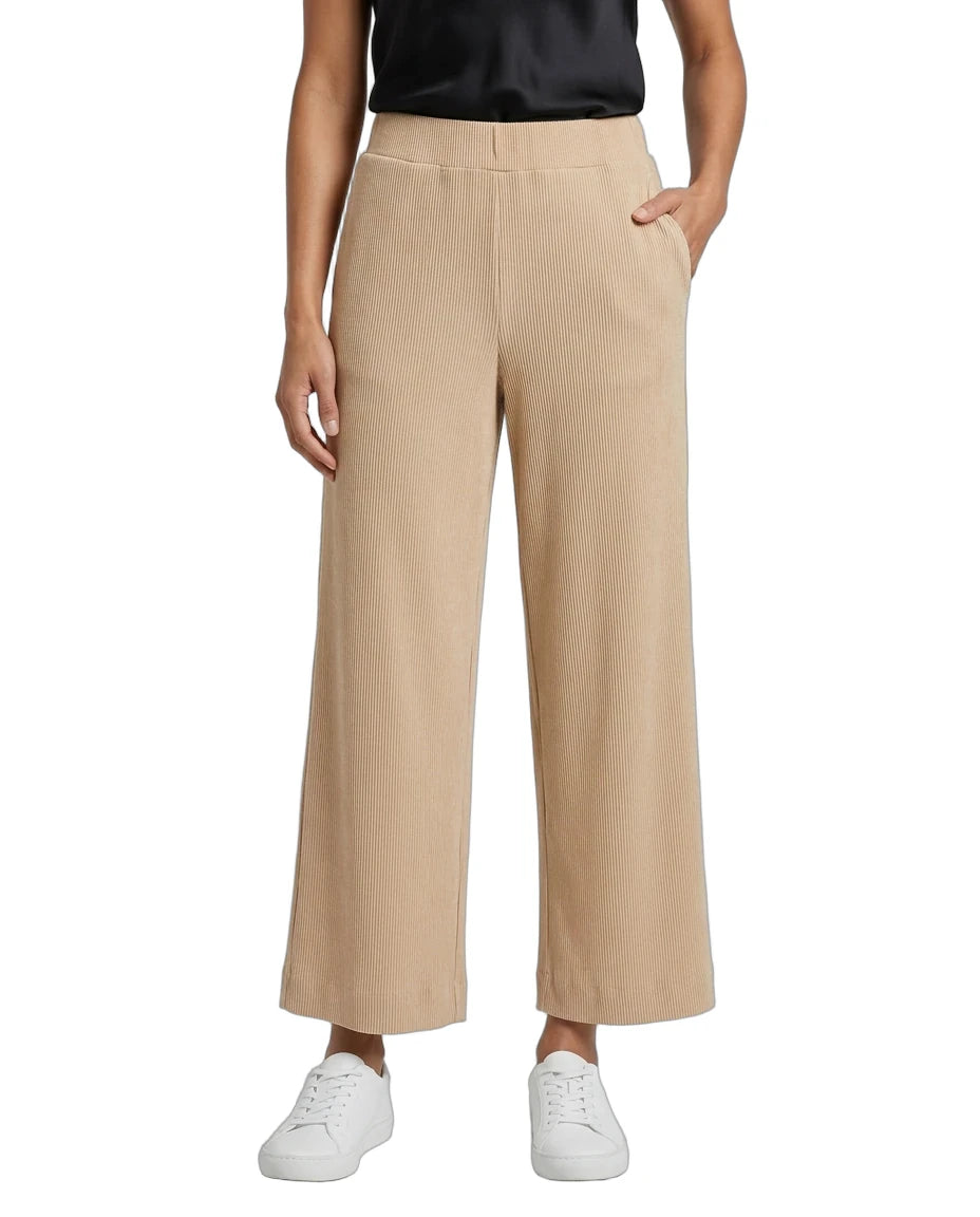 A model wearing beige wide-leg cropped trousers with a black satin top and white sneakers, shown from the waist down on a white background.