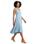A woman modeling a sleeveless light blue V-neck midi dress with a flared skirt, paired with tan heeled sandals, against a plain white background.