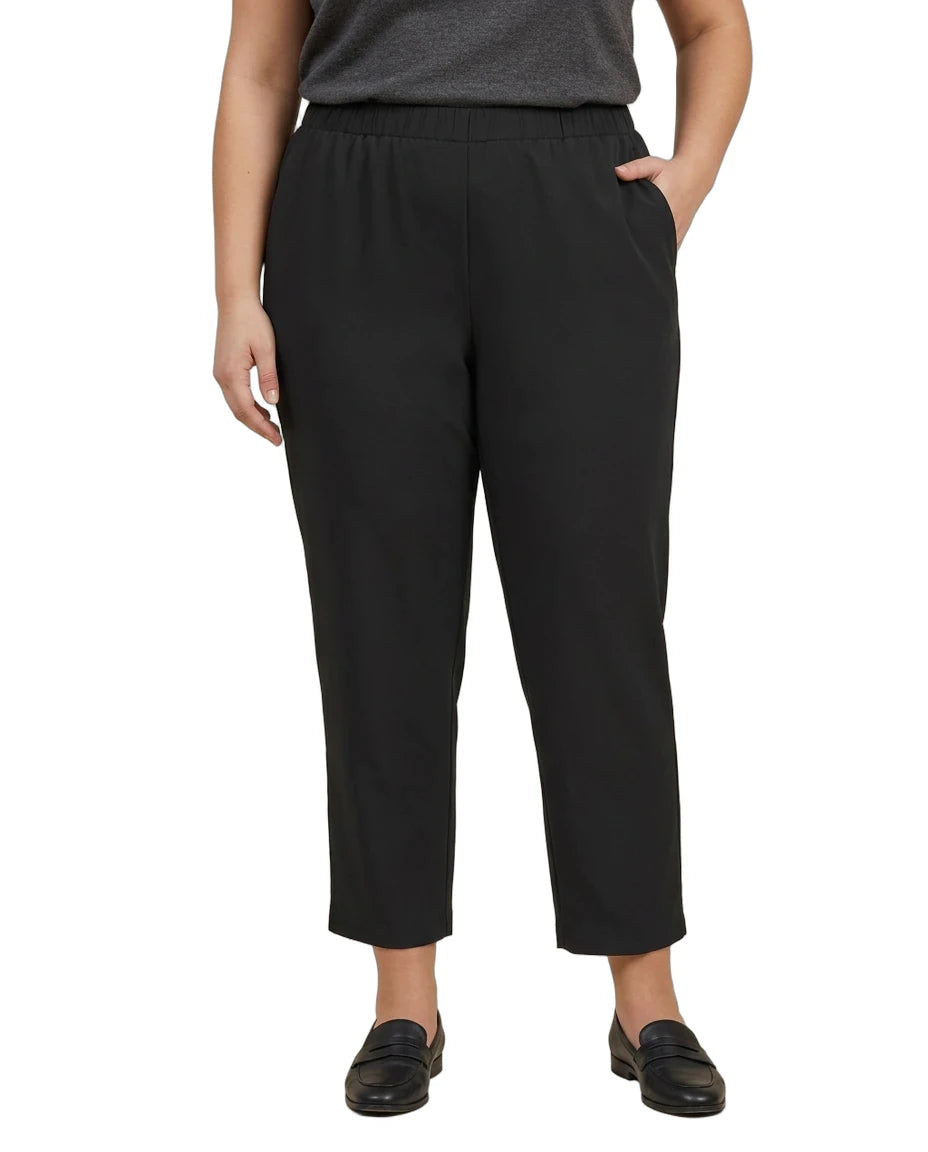A model wearing black cropped pants with an elastic waistband, paired with a dark gray top and black loafers, shown against a plain white background.