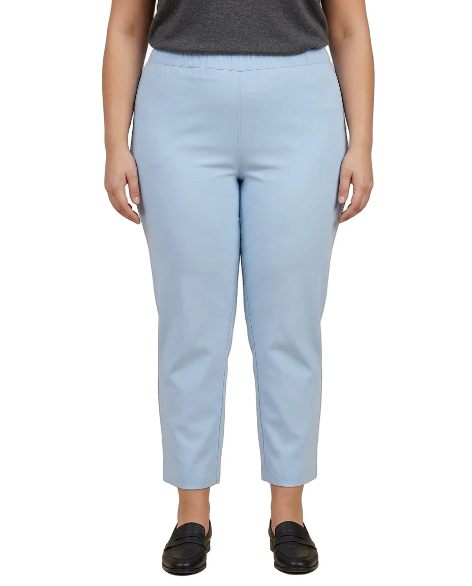 A person wearing light blue cropped pants with a dark gray top and black slip-on shoes, shown from the chest down against a plain white background.