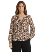 Woman wearing a brown and beige patterned blouse on a white background