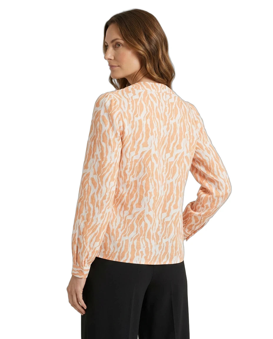Woman wearing a long-sleeve, patterned blouse with a white background