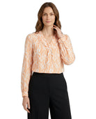 Woman wearing a patterned blouse and black pants on a white background