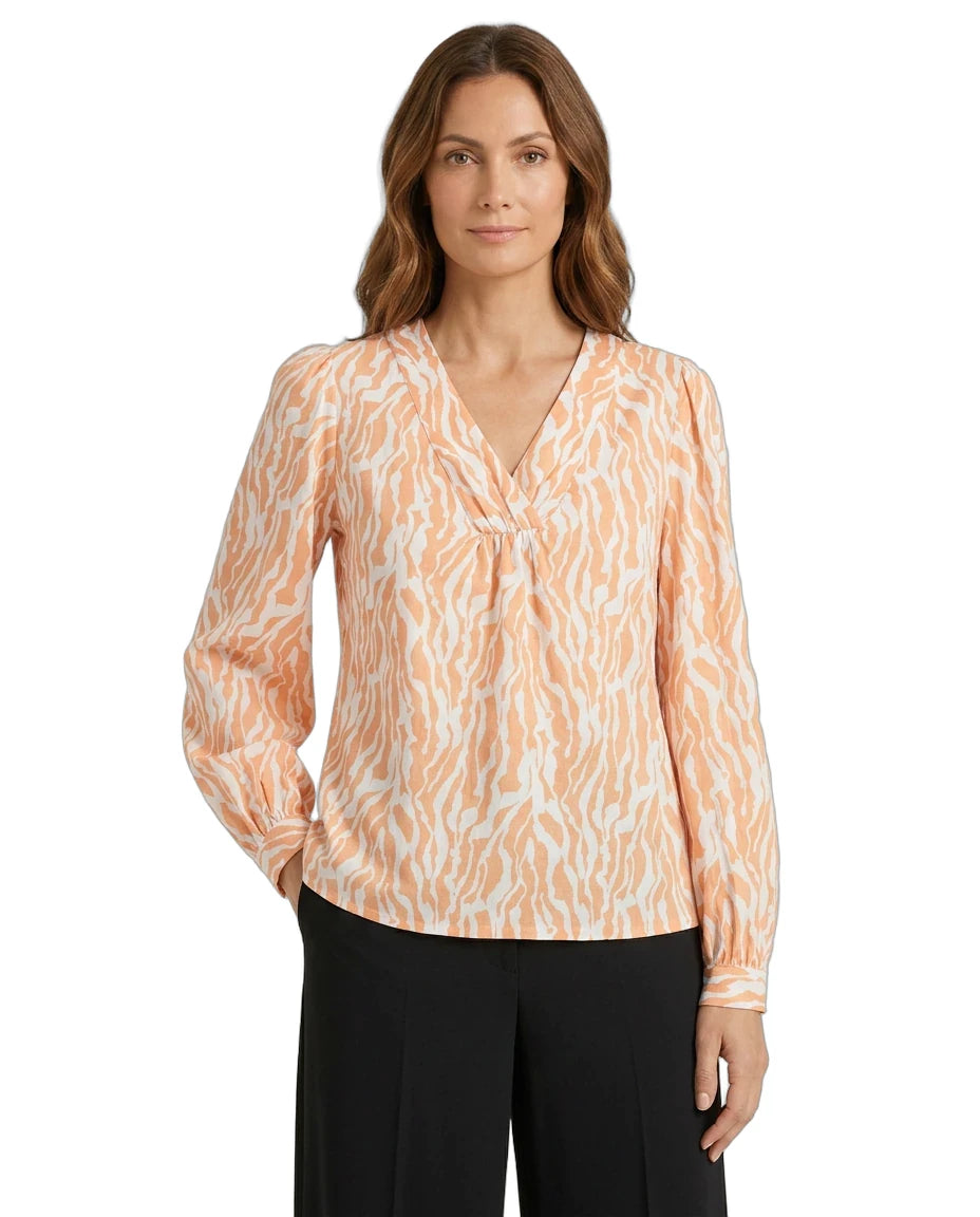 Woman wearing a patterned blouse with long sleeves on a white background
