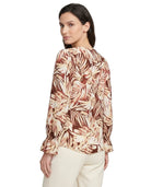 Woman wearing a patterned blouse with a white background