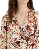 Woman wearing a floral patterned blouse with a plain background
