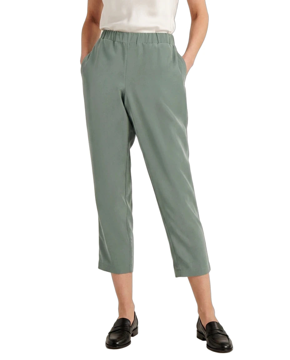 A model wearing sage green cropped pants with an elastic waistband, paired with a white top and black loafers, shown from the waist down on a white background.