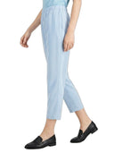 A person wearing light blue cropped trousers with an elastic waistband, paired with a light blue top and black loafers, shown against a plain white background.