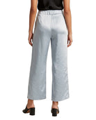 A model from the back wearing light blue wide-leg cropped trousers with a satin-like sheen, paired with a black top and black block-heel mules, against a plain white background.