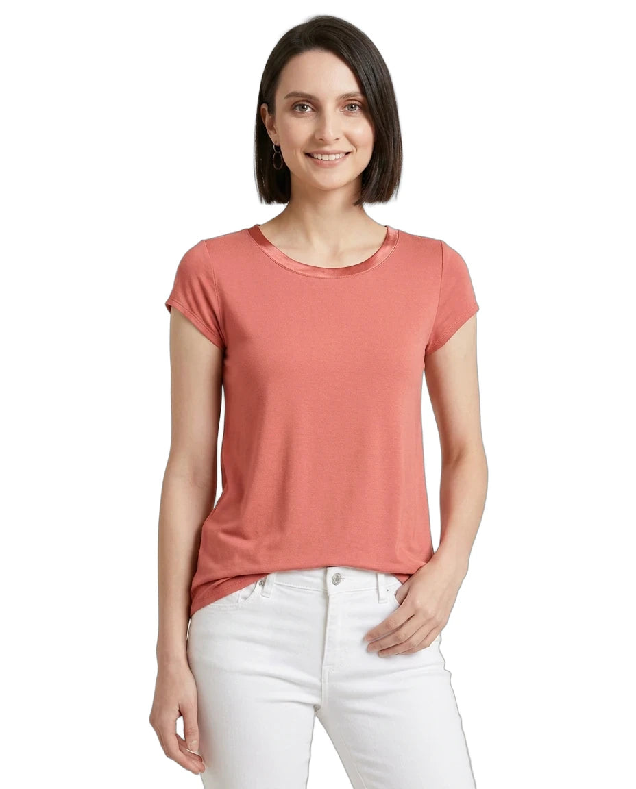 Woman wearing a coral t-shirt and white pants on a white background