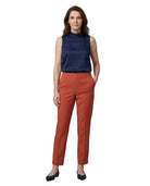 A woman modeling a sleeveless navy blue mock-neck top and rust-orange cropped trousers with black flats, shot against a plain white background.