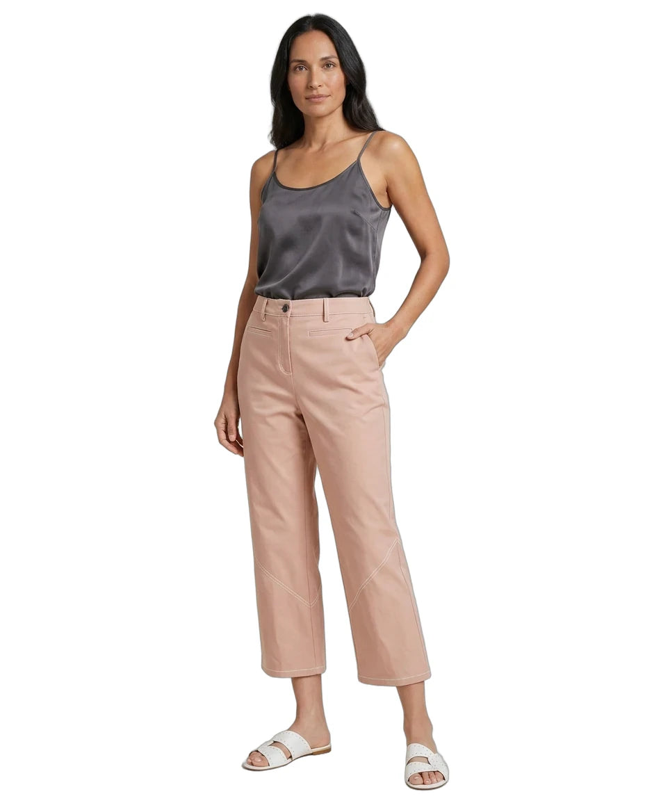 A woman modeling a pair of light blush pink cropped pants with a dark gray satin camisole and white slide sandals, set against a plain white background.