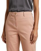 A close-up of a model wearing dusty pink tailored trousers with belt loops, a button closure, and front welt pockets, paired with a dark gray top against a white background.