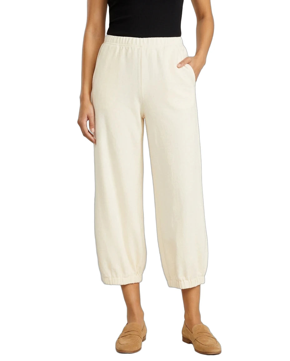 A model wearing a pair of cream-colored cropped wide-leg pants with an elastic waistband and side pockets, paired with a black top and tan loafers, against a plain white background.
