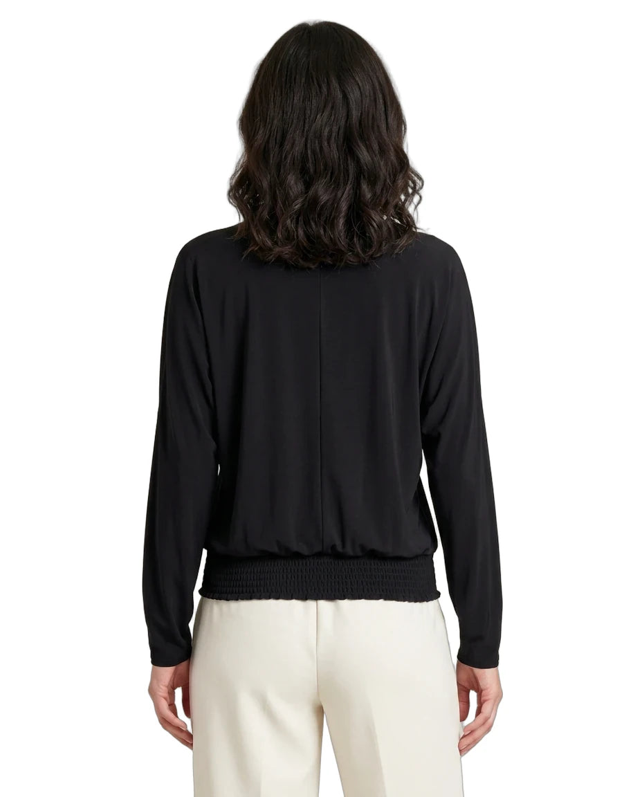 Person wearing a black long-sleeve top and white pants on a white background