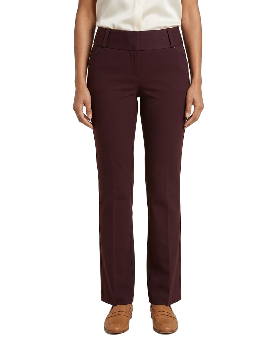 A model wearing a pair of high-waisted, straight-leg trousers in a deep burgundy color, paired with a cream blouse and tan loafers, against a plain white background.