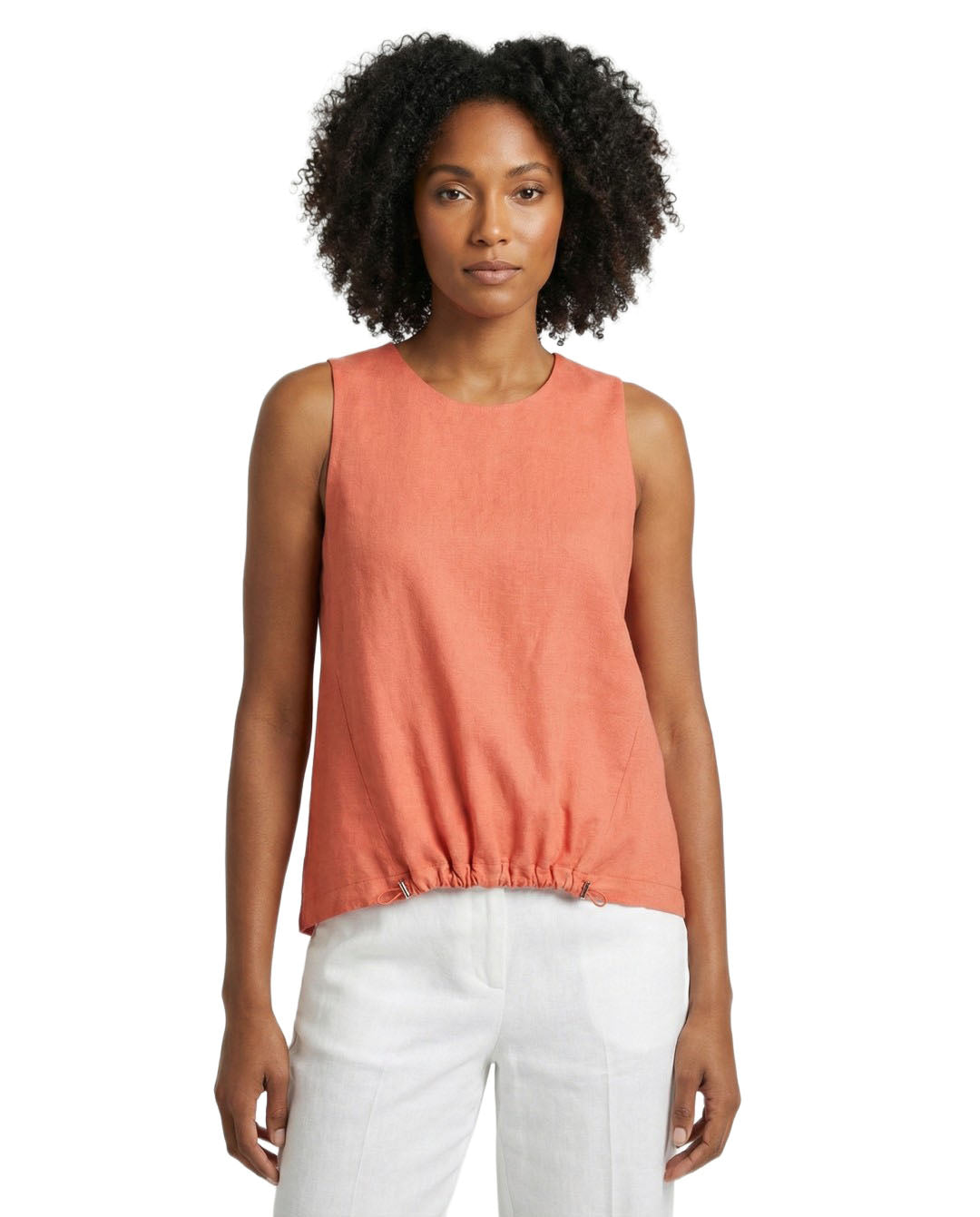 Woman wearing a coral sleeveless top and white pants on a white background
