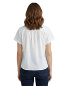 Woman wearing a white blouse and dark jeans on a white background