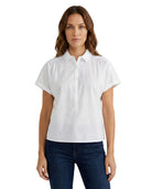 Woman wearing a white short-sleeve blouse and dark jeans on a white background