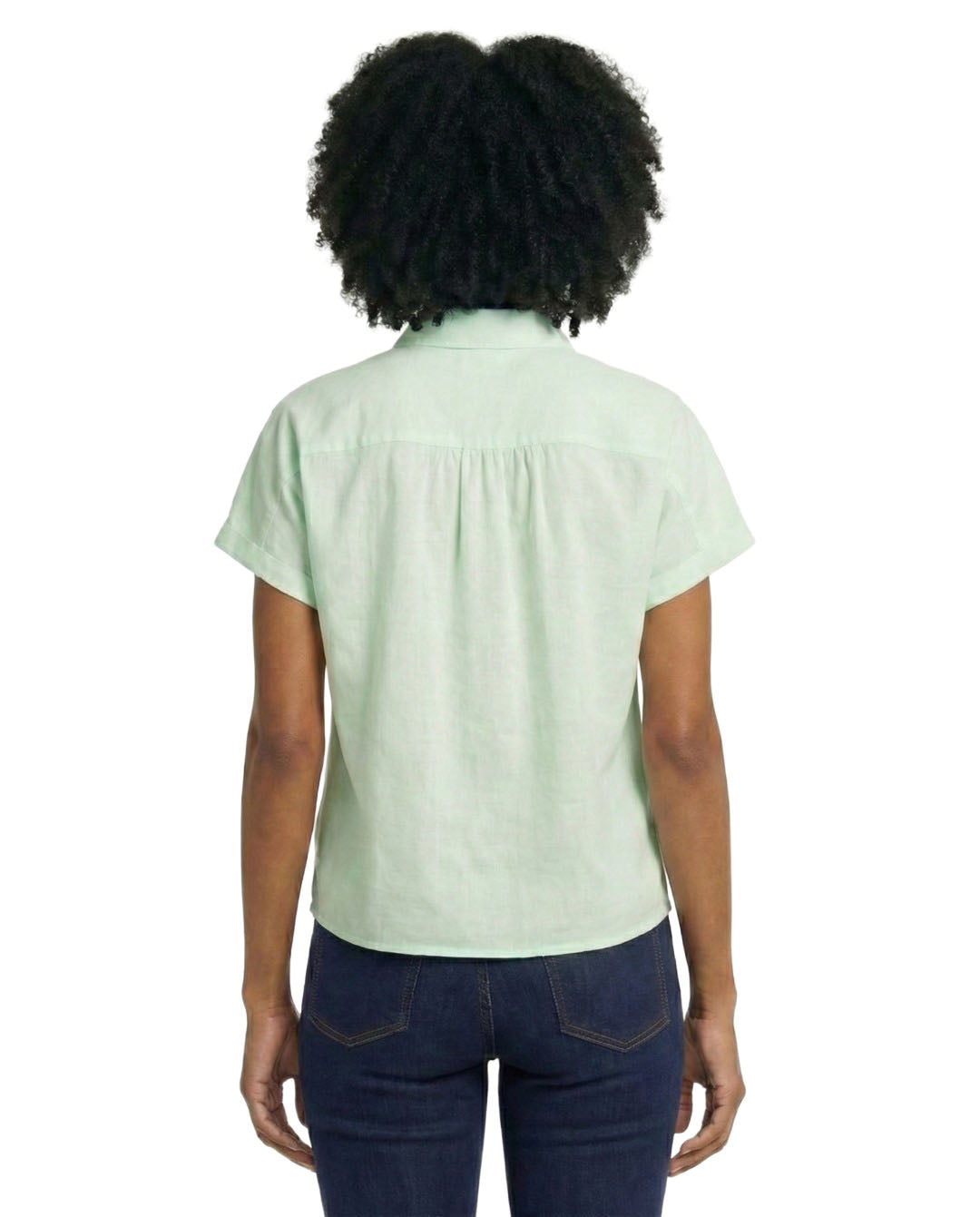 Person wearing a light green shirt and dark blue jeans on a white background