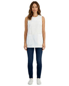 Woman wearing a white sleeveless top and dark blue pants on a white background
