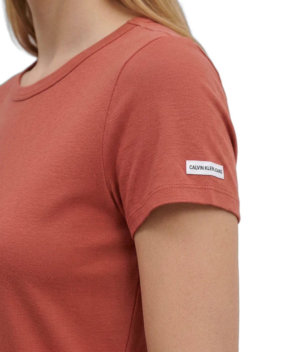 Person wearing a red t-shirt with a Calvin Klein label on a white background